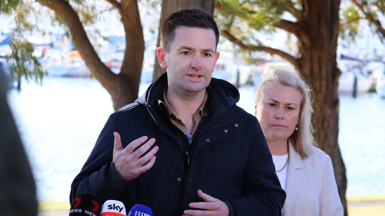 Labor leader Dean Winter and re-elected MP Anita Dow speak to media at a press conference in front of a body of water.