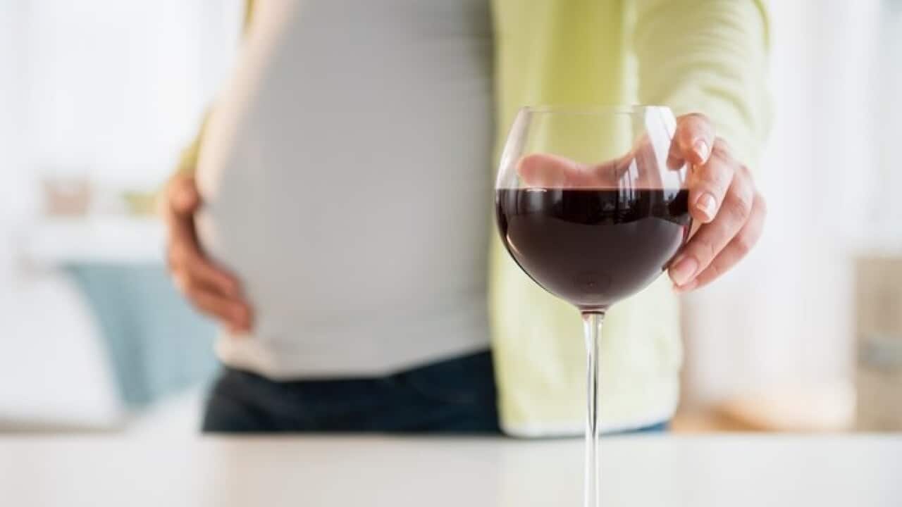 Pregnant woman with glass of red wine