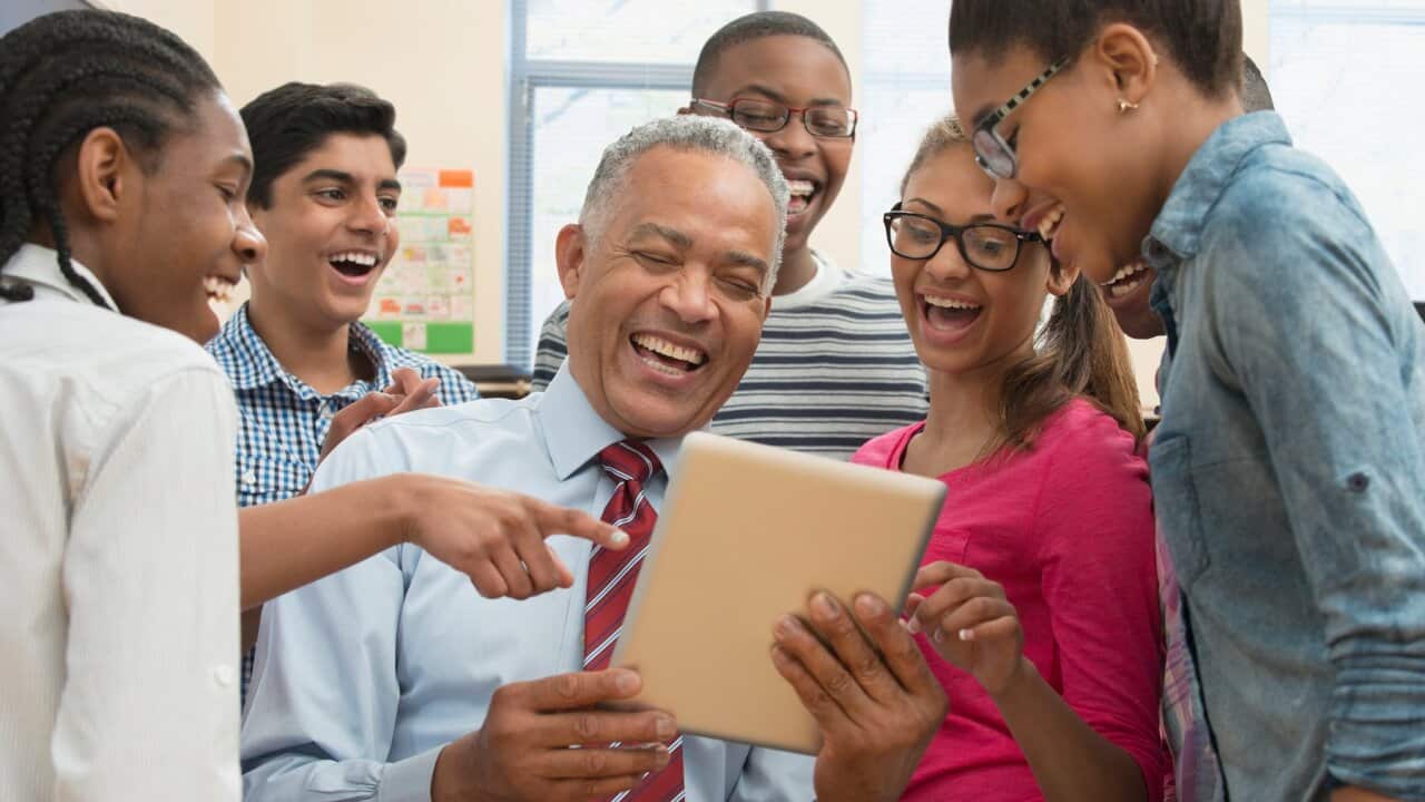 Teacher and students using digital tablet in classroom