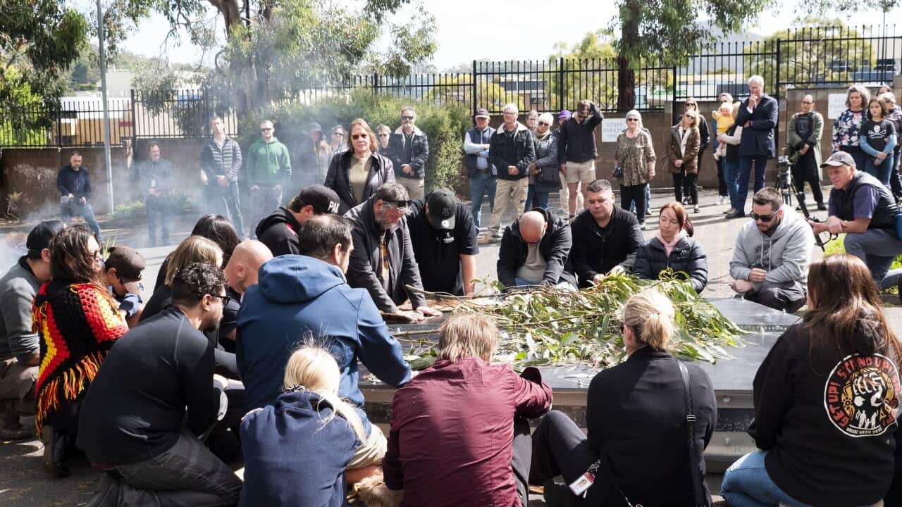 Members of the Tasmanian Aboriginal community gather around the petroglyph before it is loaded onto the truck. (Sarah Maunder, SBS).jpg