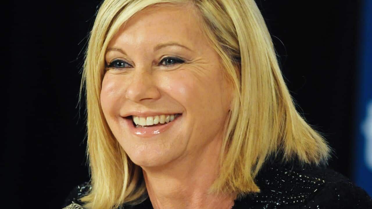 A woman speaking while seated in front of a microphone.