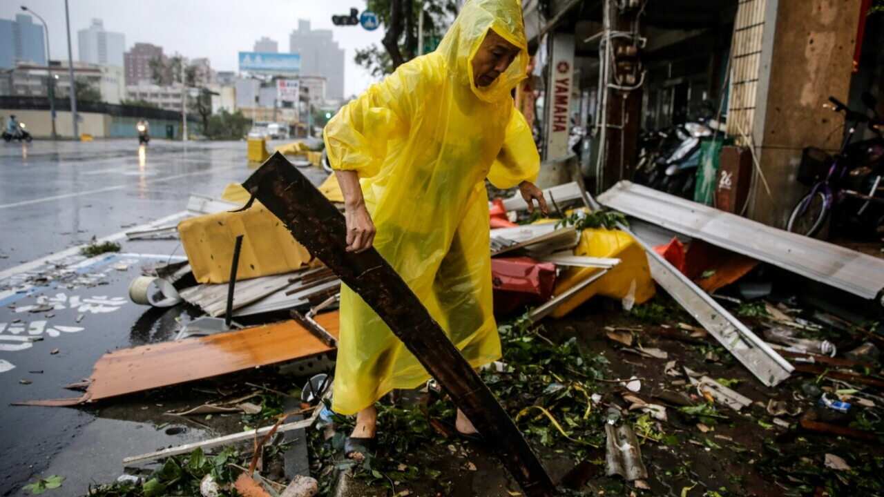 A man salvages usable materials from debris after strong winds and rain from Super Typhoon Meranti in Kaohsiung, southern Taiwan (AAP)