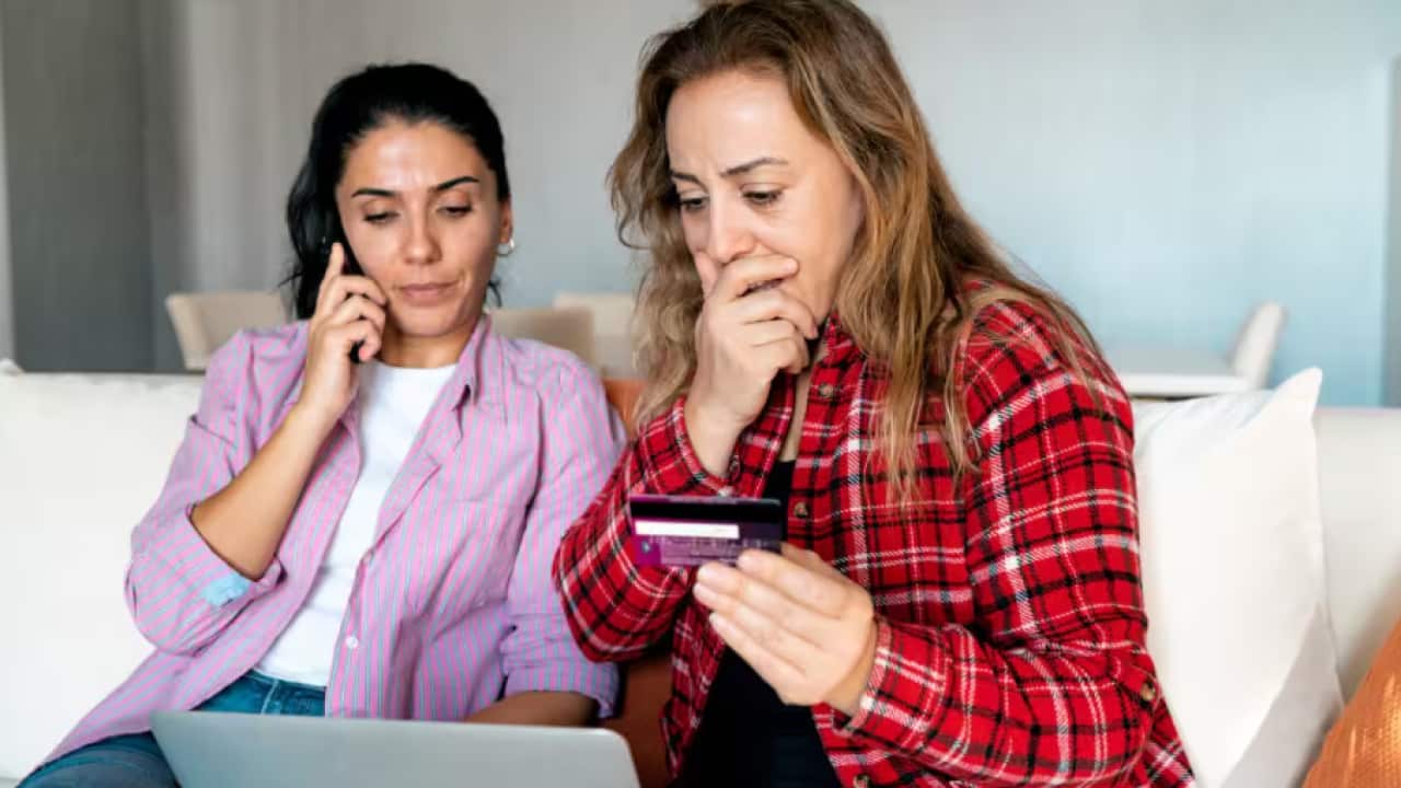 Stressed upset woman holding bank card and being surprised