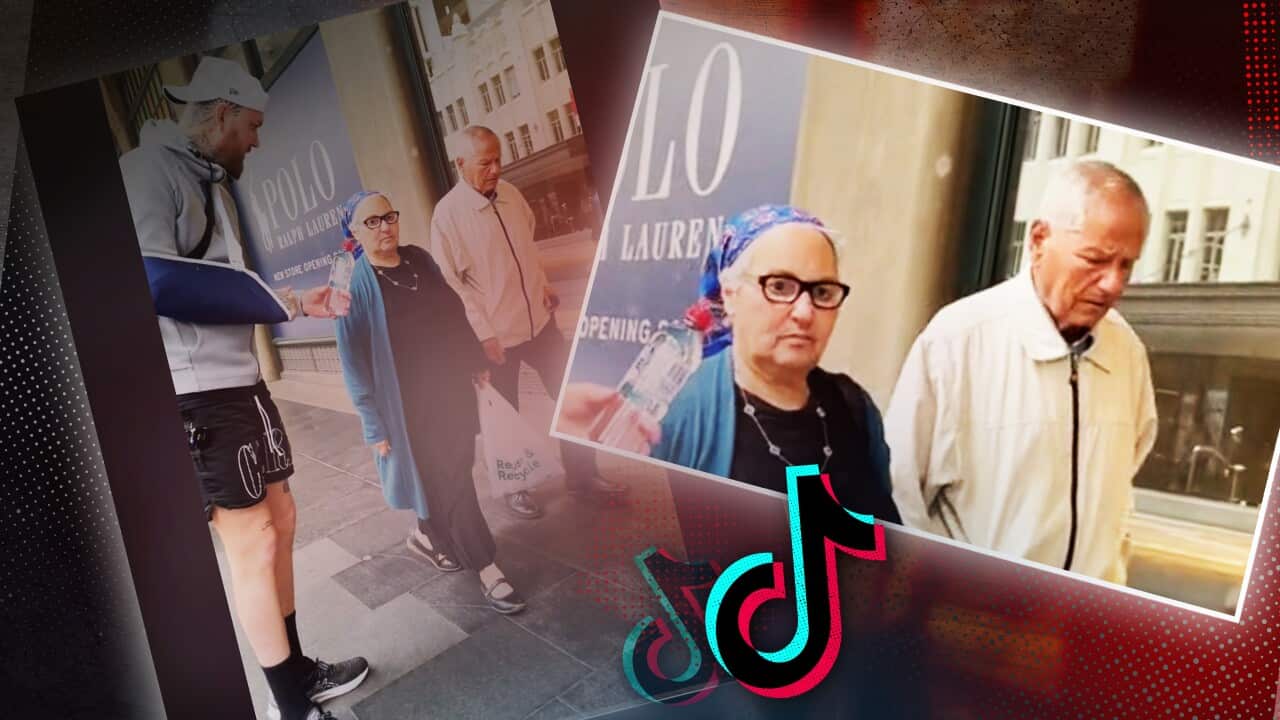 A man with his arm in a sling handing a water bottle to a couple