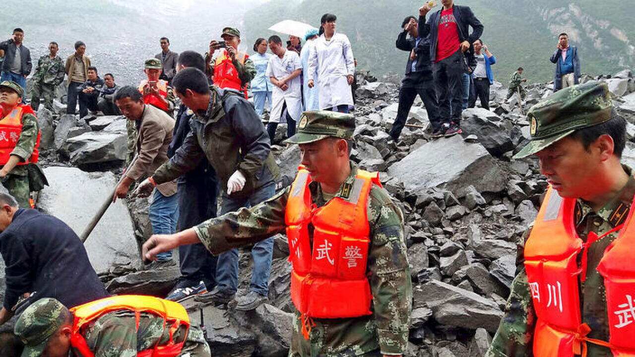 Emergency personnel and local people work at the site of a landslide in Xinmo village in Maoxian County in southwestern China's Sichuan Province