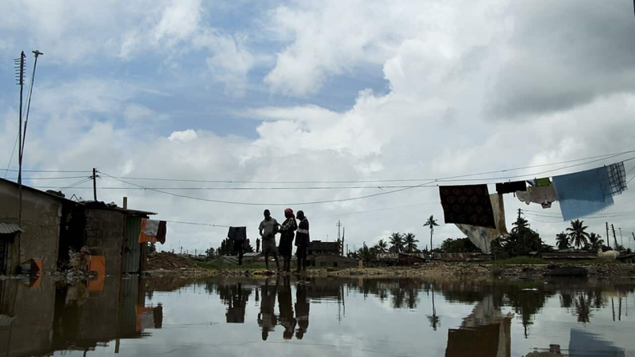Residents stand outside their flooded home in Dar es Salaam