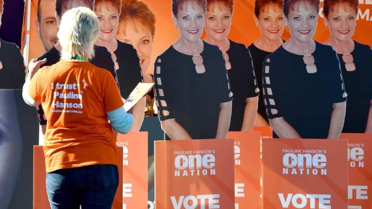 A One Nation volunteer adjusts cardboard cutouts of Pauline Hanson.