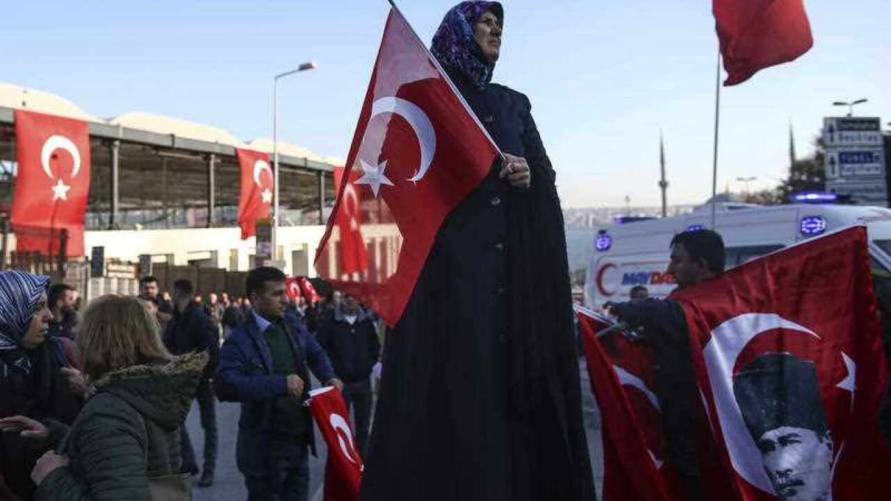 People gather outside the Besiktas football club stadium Vodafone Arena decorated with Turkish flags in Istanbul, Sunday, Dec. 11, 2016.