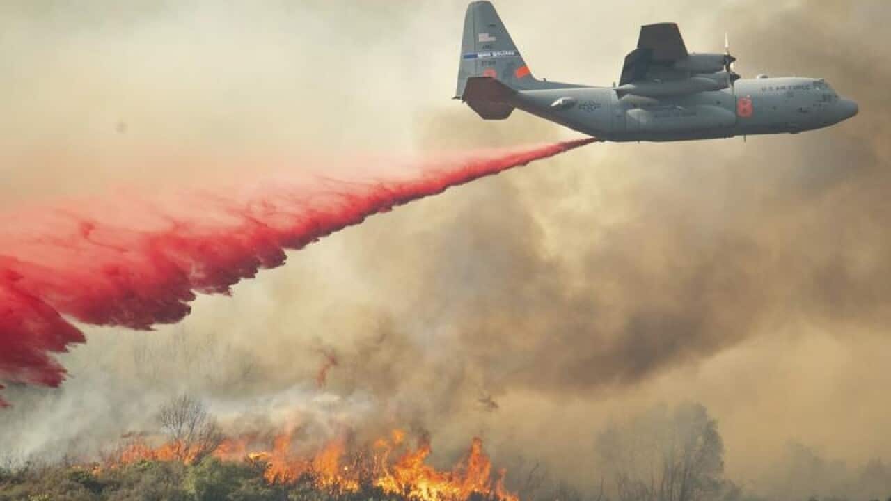 A US Air Force plane drops fire retardant on a hillside in California