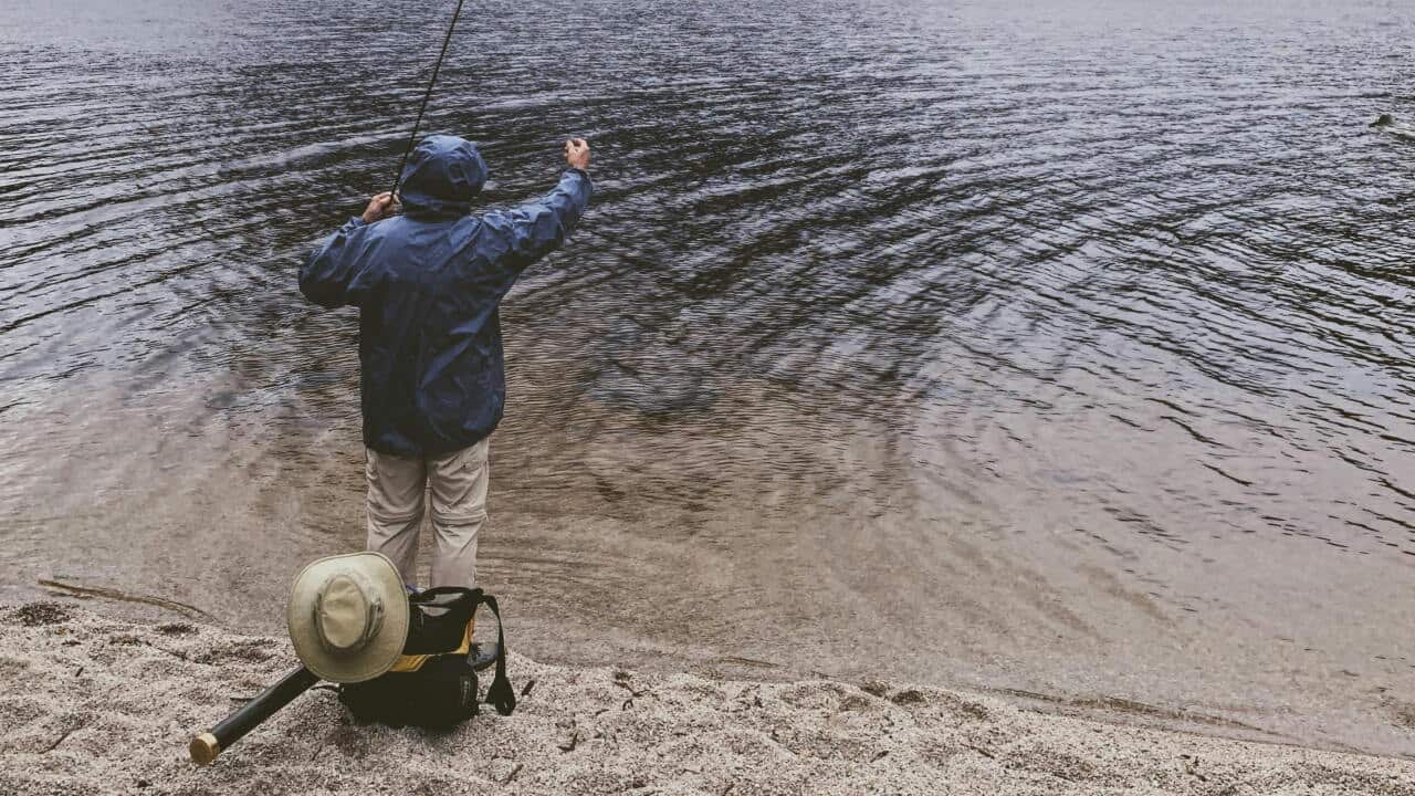A man fishing at Cradle Mountain Lake, Tasmania.