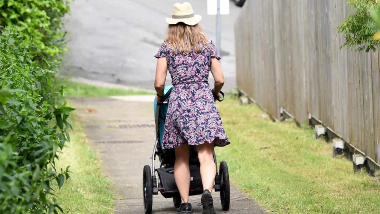 A mother pushes a stroller after picking up her child early from childcare as educators walk off the job in protest in Brisbane, Tuesday, March 27, 2018.