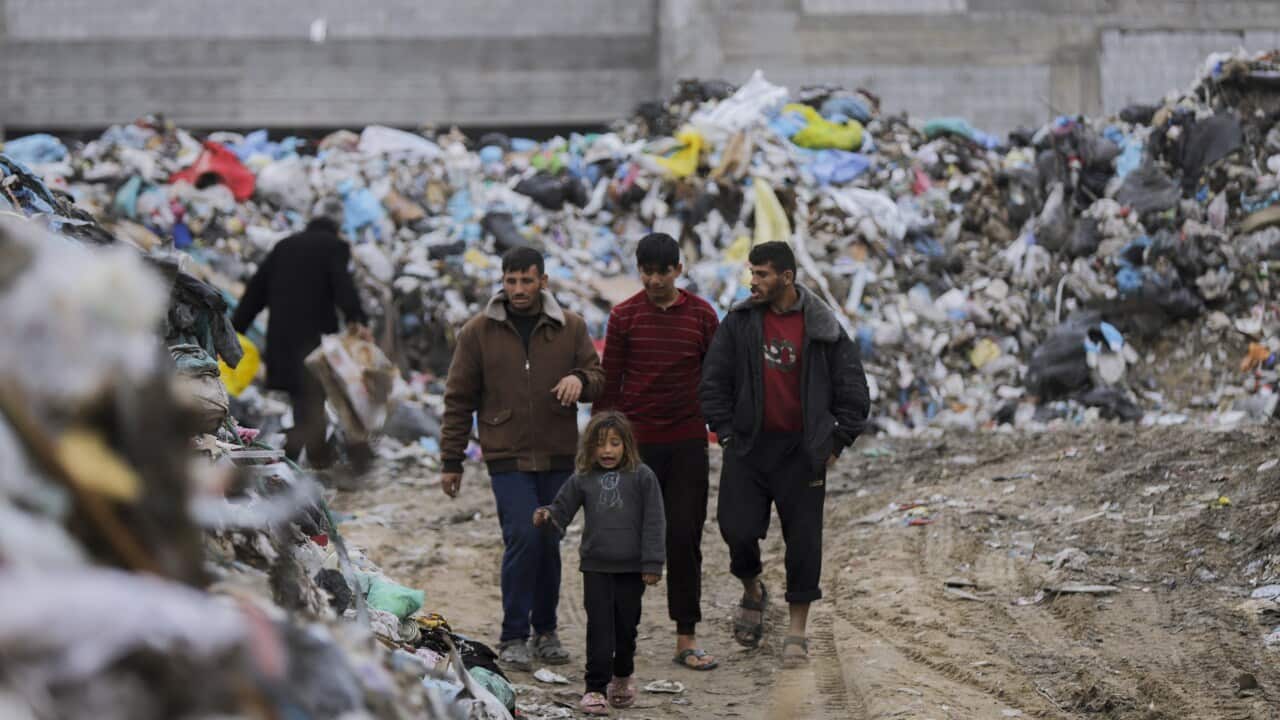 三個大人和一個小孩走在被瓦礫和垃圾包圍的路上。