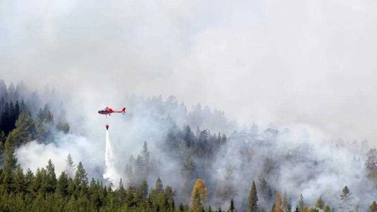 A picture made available on 17 July 2018 shows a helicopter water-bombing a forest fire raging in Hammarstrand, Sweden, 16 July 2018.