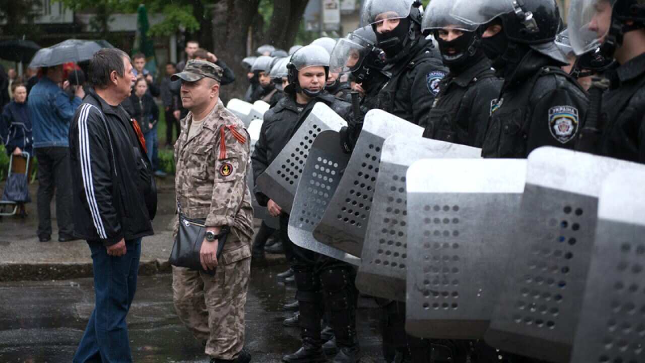 A pro-Russian militant walks in front of police in formation