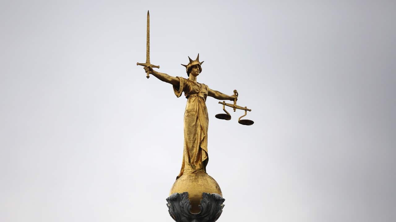A statue of the scales of justice stand above the Old Bailey