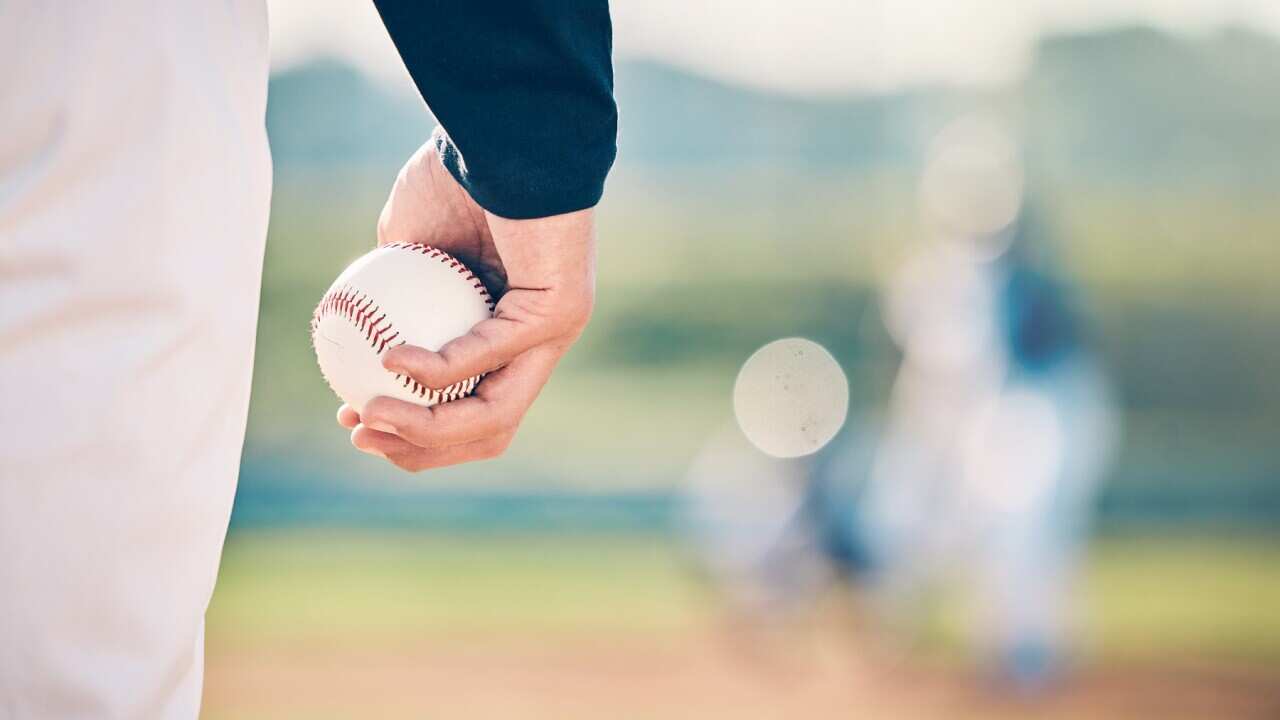 Baseball player, ball and athlete or pitcher hand in a competitive match or game on the sports field for training. Closeup, sportsman and person playing a sport or softball as exercise and fitness