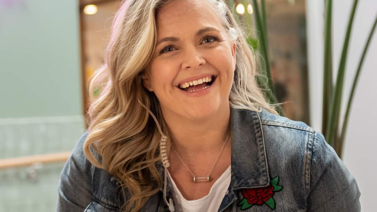 Taryn Brumfitt sitting in an office holding a camera