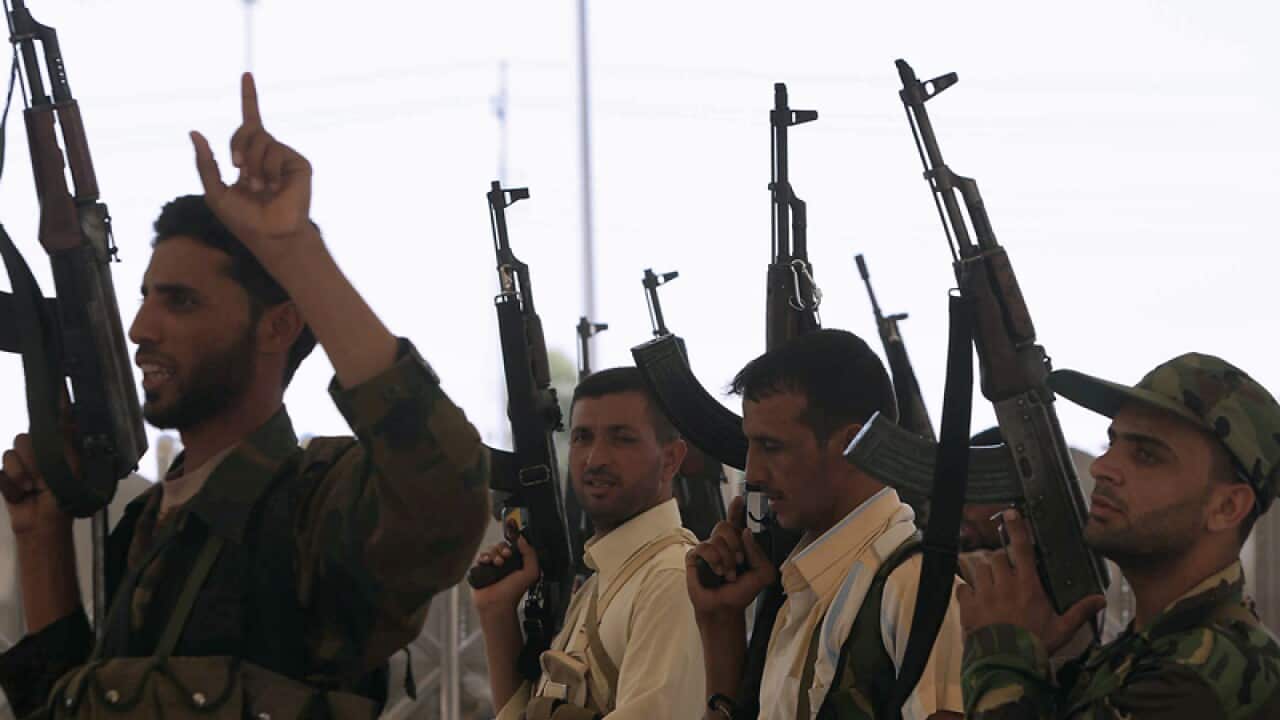 Iraqi Shiite men parade their weapons