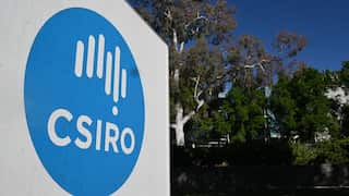 A white sign with the light blue CSIRO logo with bushland in the background