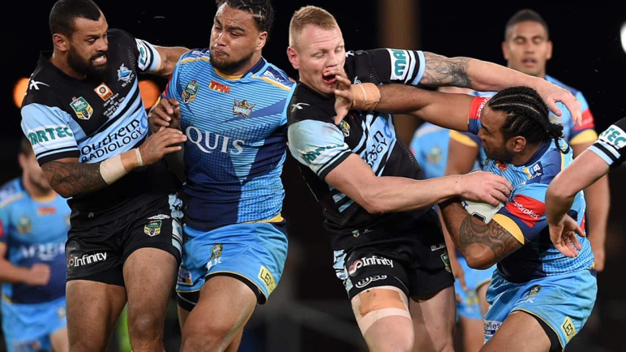 Zen Taia of the Gold Coast Titans is tackled by Sharks' James Maloney