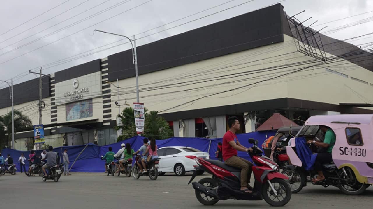 Filipino motorists drive past a damaged shopping mall, Surigao