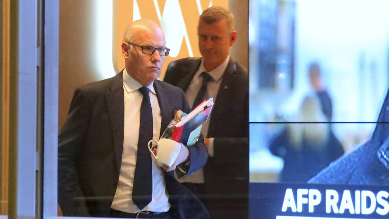 John Lyons (left), Executive Editor of ABC News, is followed by an Australian Federal Police officer as they walk out the main entrance to the ABC building