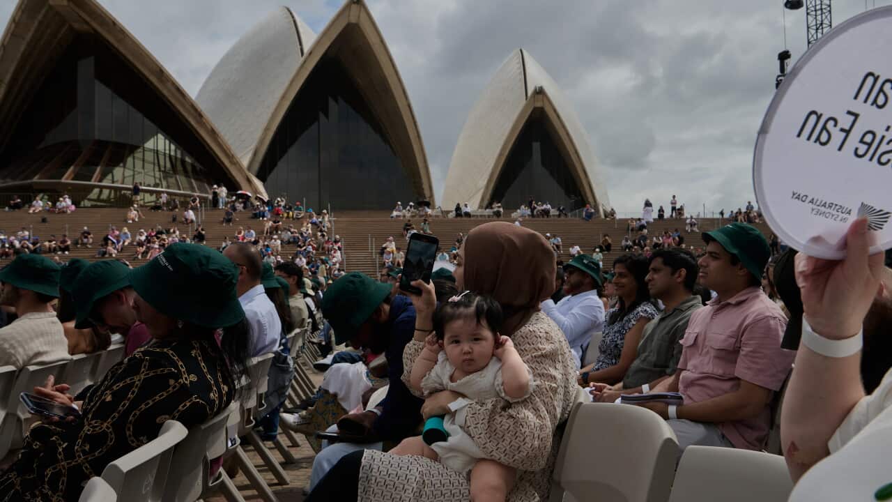 A mother holds a child in front of the Sydney Opera House for a citizenship ceremony