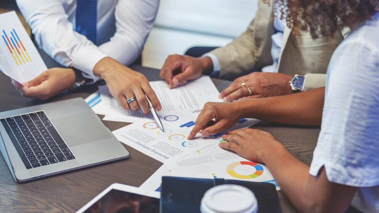 Close up of people pointing to a graph with data.