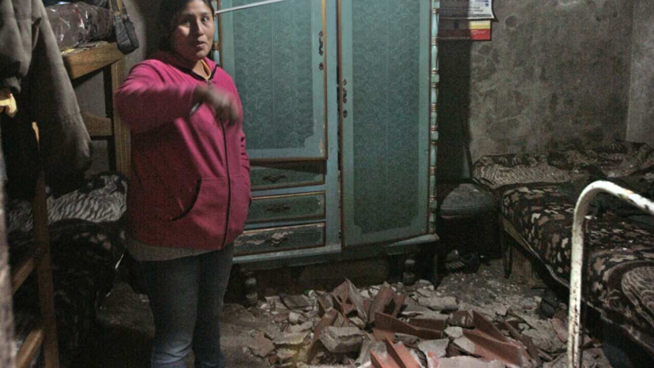 A lady stands in her house in after it was damaged by an earthquake
