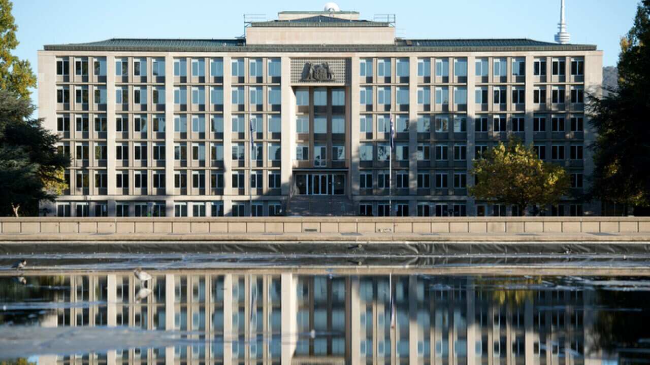 The Department of Treasury is seen reflected in a fountain in Canberra