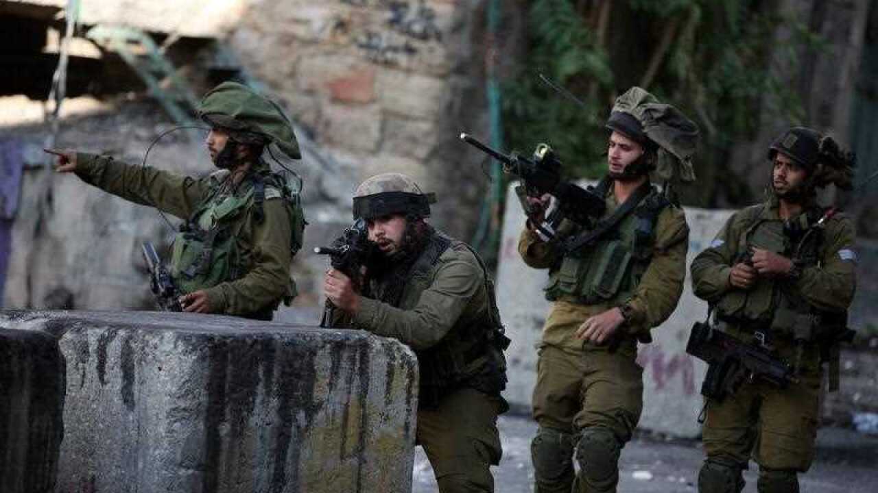 Members of the Israeli armed forces take up positions during clashes with Palestinian protesters in the West Bank city of Hebron