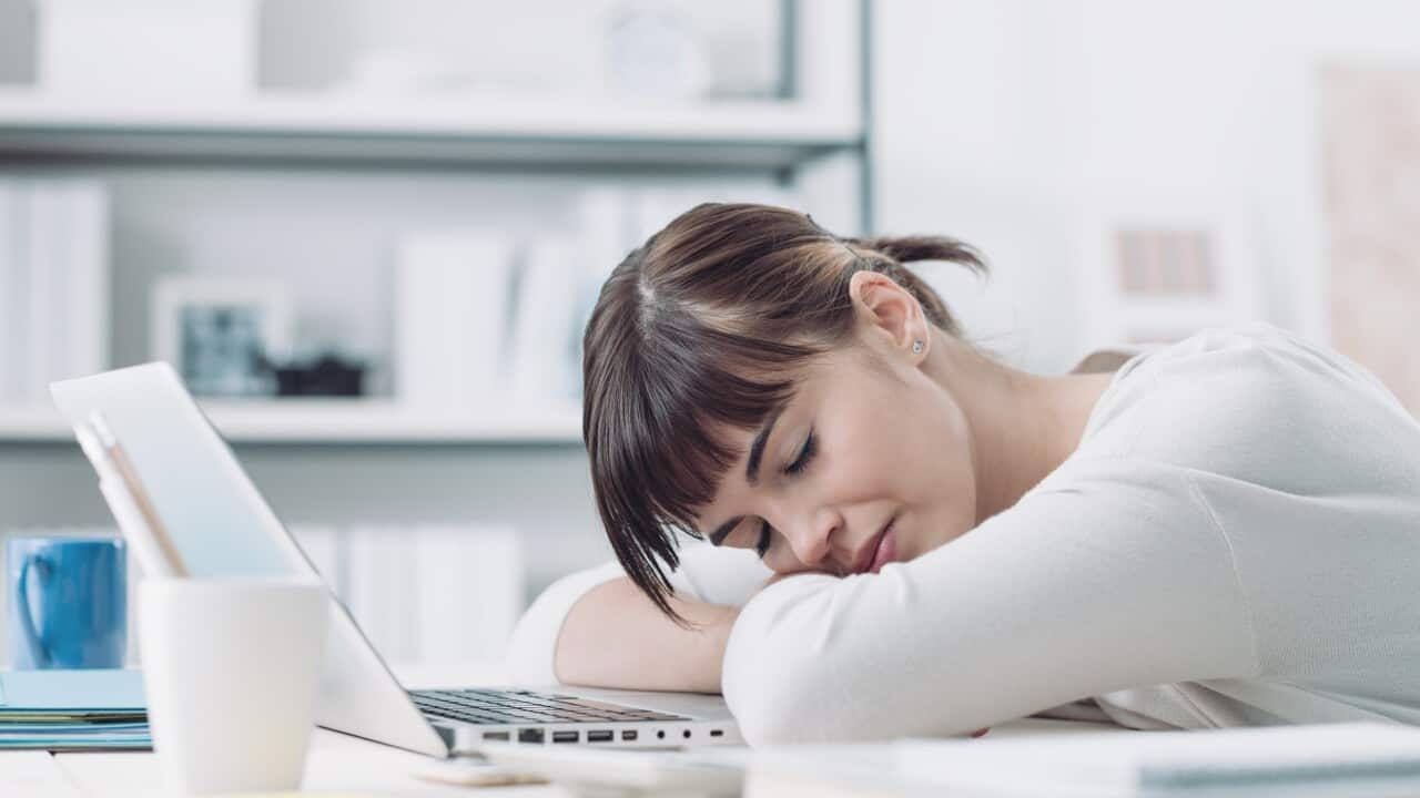 Young tired woman at office desk sleeping with eyes closed, sleep deprivation and stressful life concept