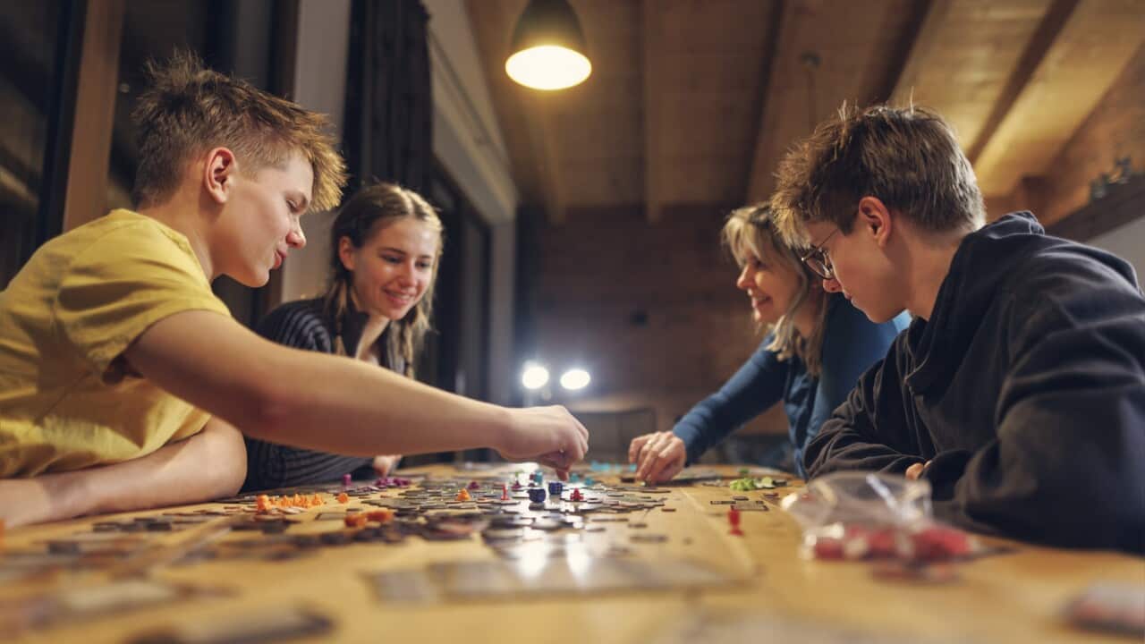 Family playing large modern board game together at home