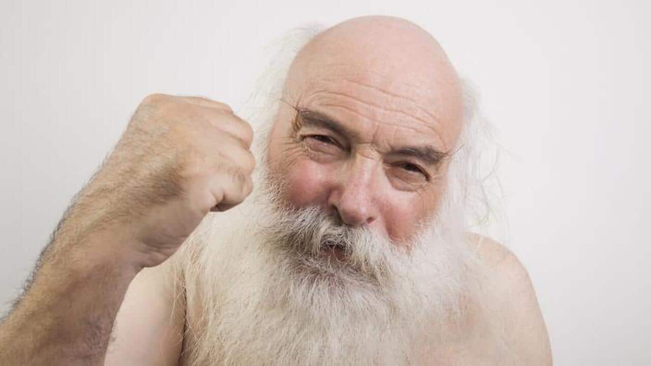 Portrait of shirtless senior man throwing a punch against white background