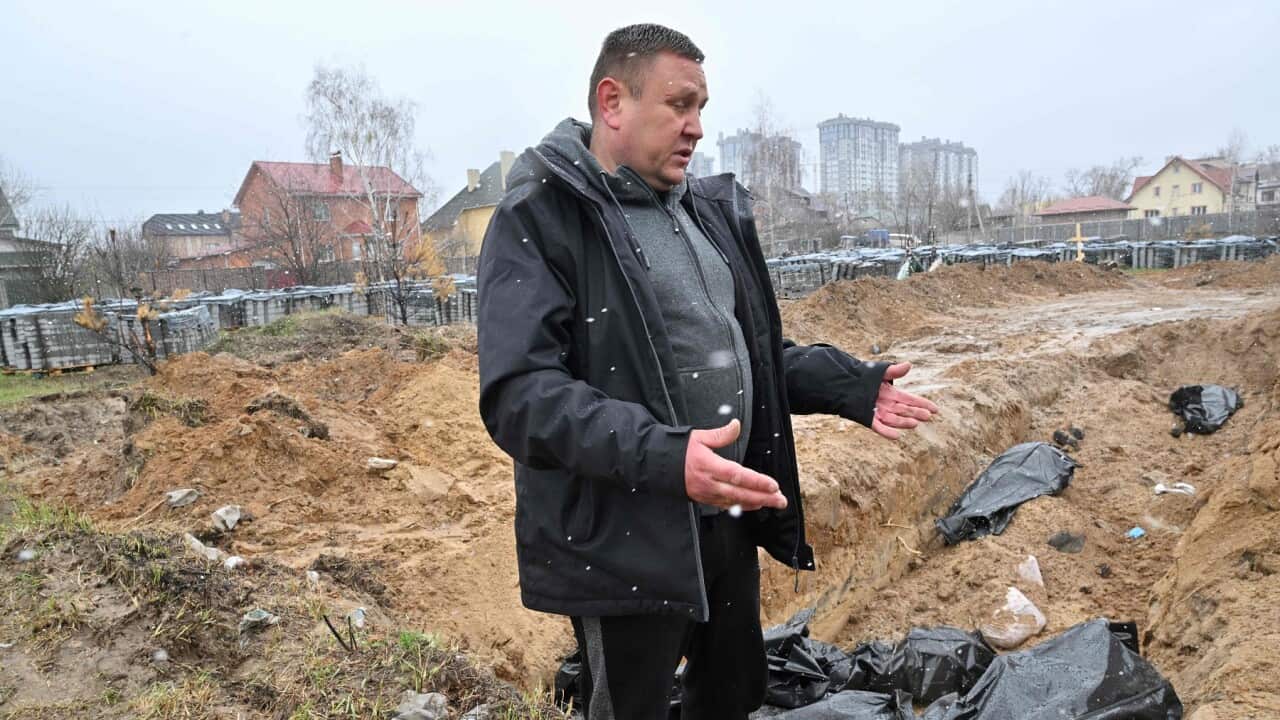 A man gestures at a mass grave in the town of Bucha