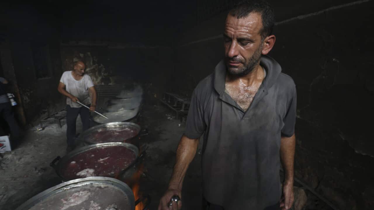 A man holds tongs over a metal plate
