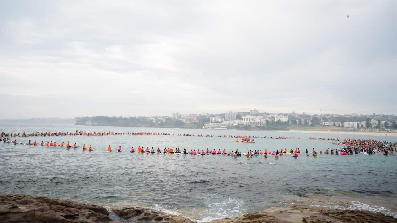 Surfers lining up in a large circle in the water