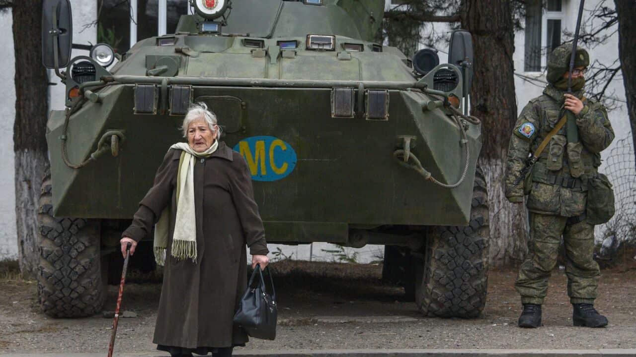 A woman walks past an APC of the Russian peacekeeping force