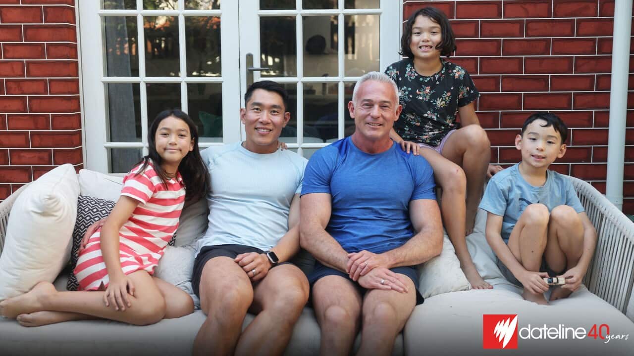 A family of two men and three children posing for a photo on a sofa