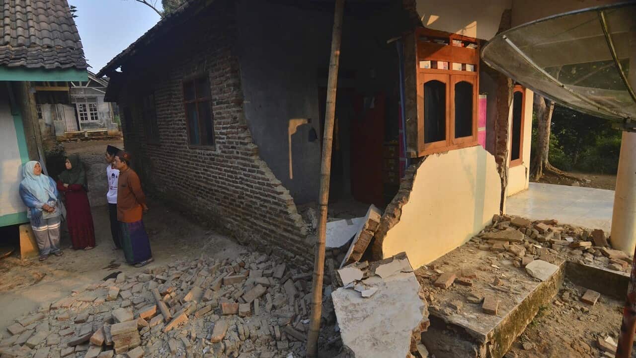 Residents talk near a house damaged in Friday's earthquake.