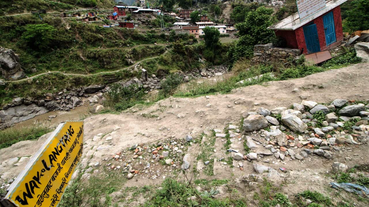 A dirt and gravel path on a ridge with a sign, water can be seen below.