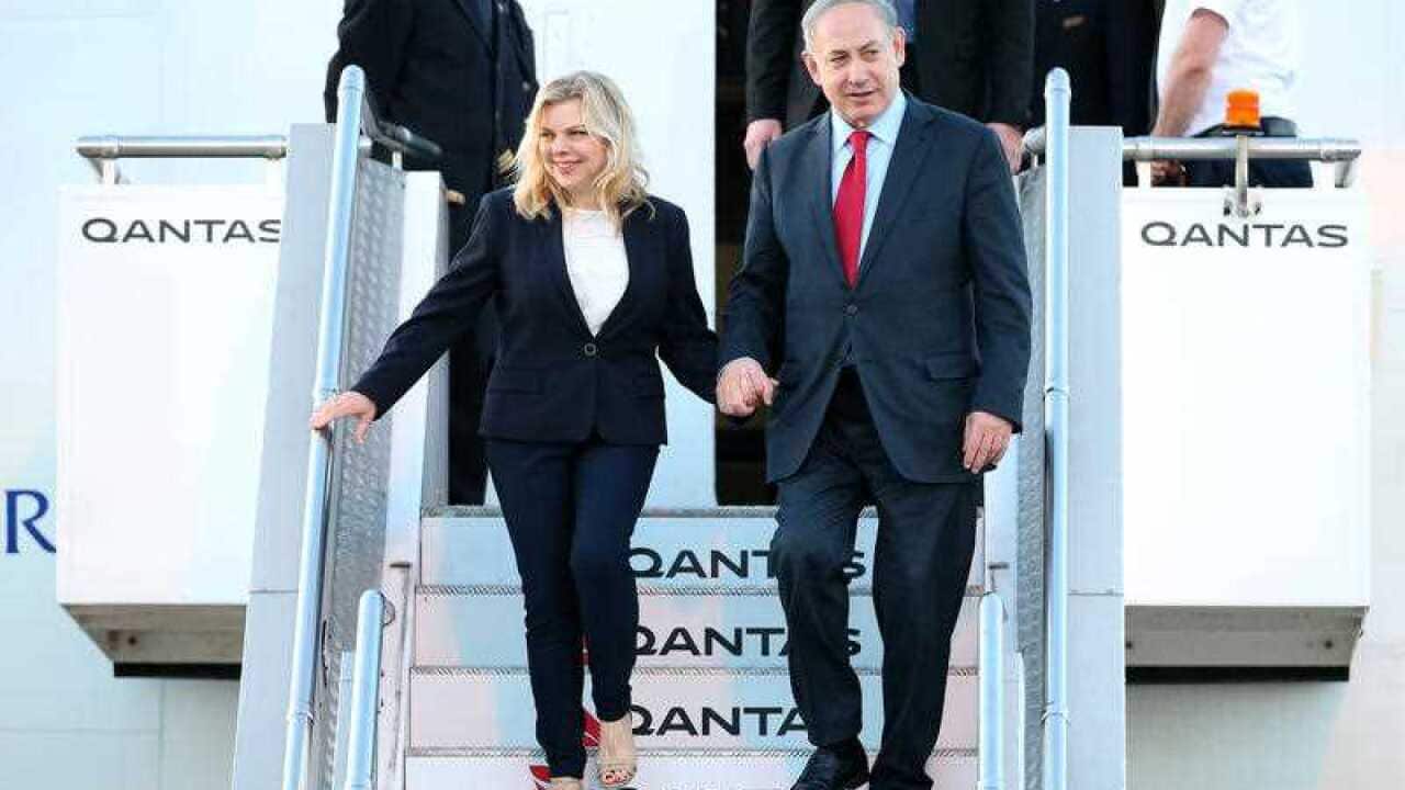 Israeli Prime Minister Benjamin Netanyahu holds hands with his wife Mrs Sara Netanyahu as they walk down steps from their aircraft after arriving in Sydney