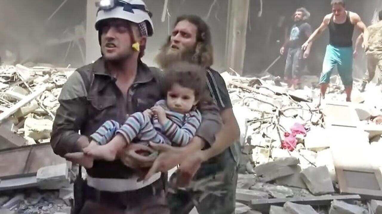 A Civil Defense worker carries a child after airstrikes hit Aleppo, Syria, Thursday, April 28, 2016.