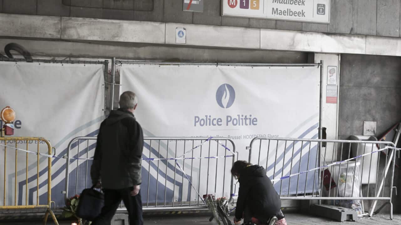 A woman lights a candle at the Maelbeek subway station in Brussels