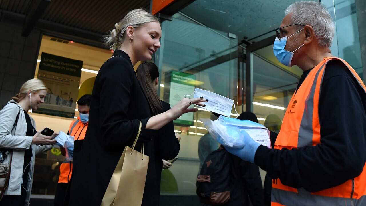 NSW Transport workers hand out face masks at Town Hall rail station in Sydney.