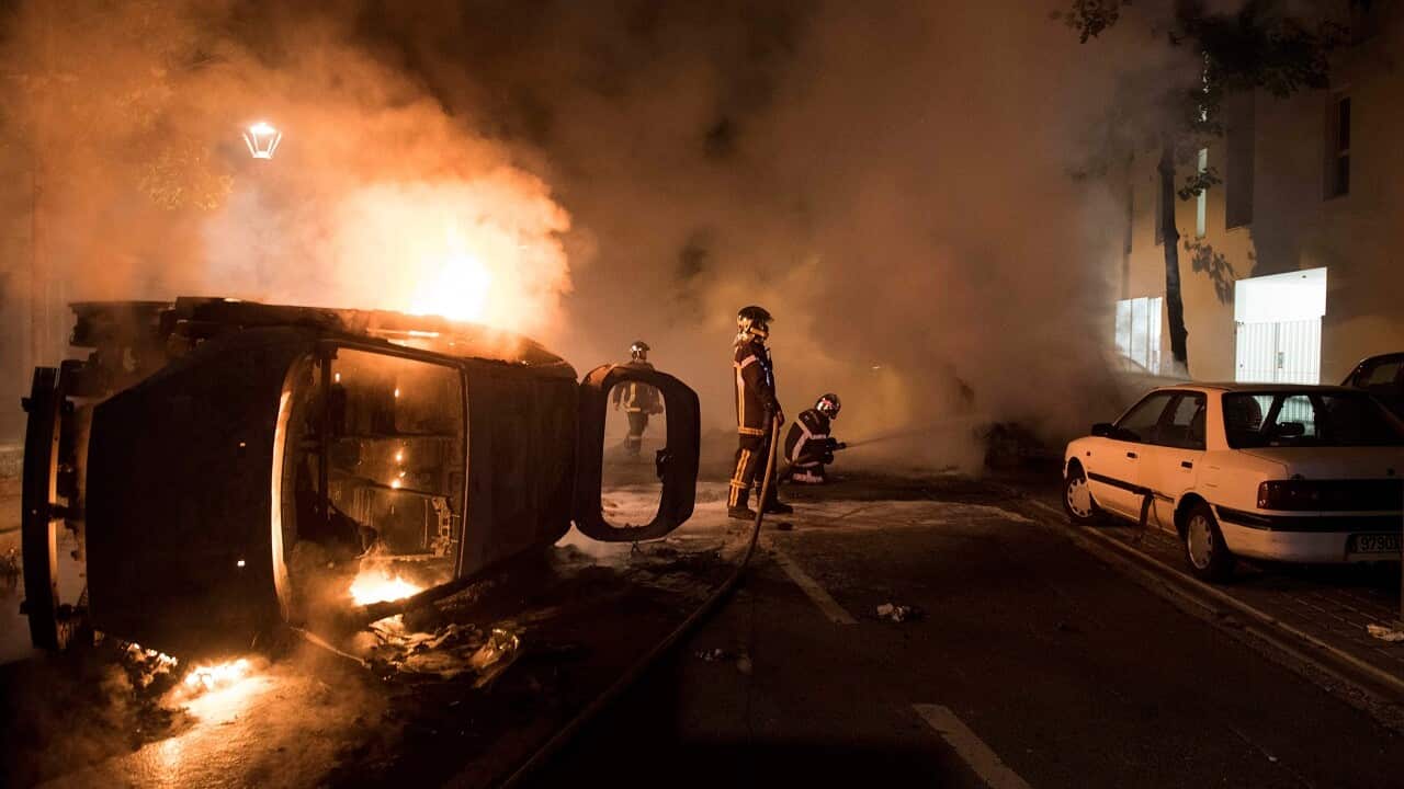 Firefighters work to put out a fire near a burning car in the Malakoff neighborhood of Nantes.
