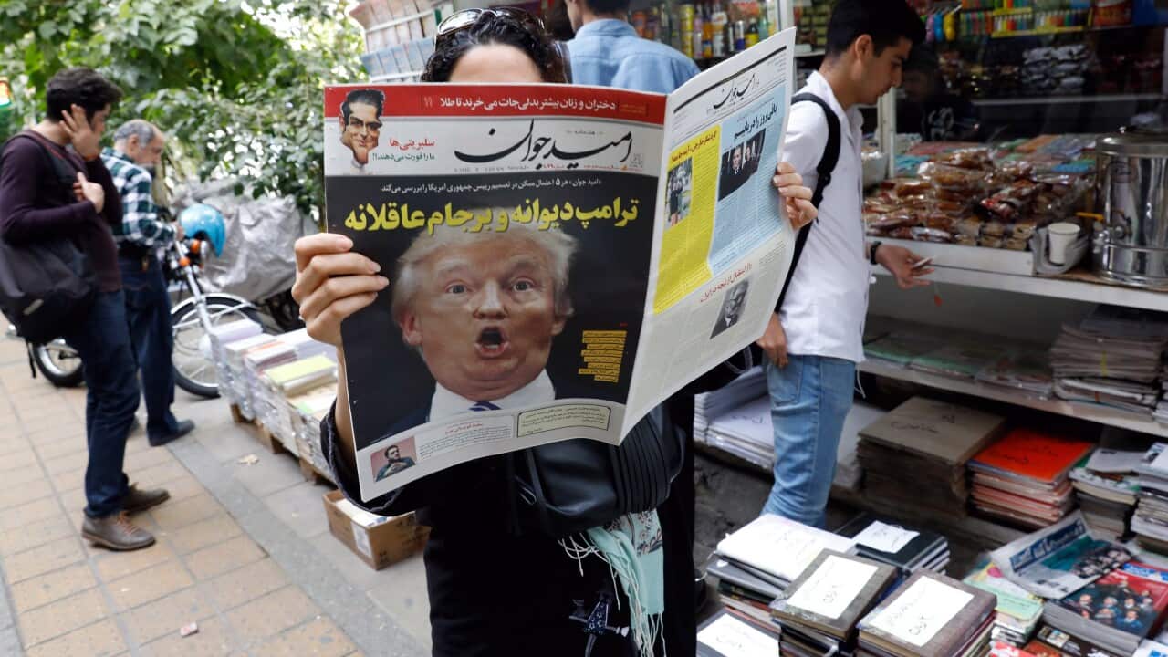 (File Image) A woman reads a copy of an Iranian daily newspaper with a picture of Donald Trump on the front page in October 2017.