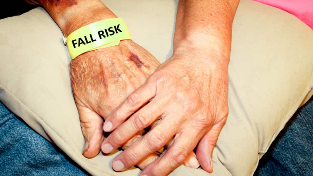 Woman holding elderly mans hand wearing a fall risk bracelet (Getty)