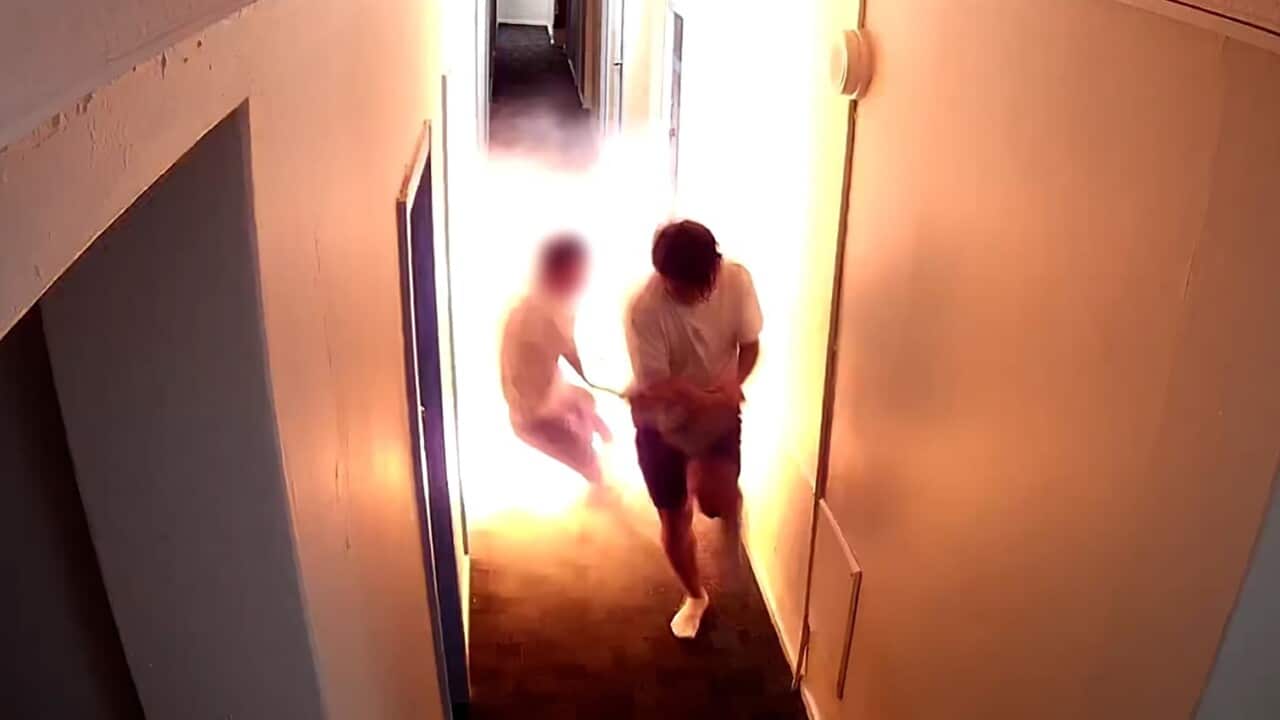 Security footage inside a hostel showing two people running away from a fire