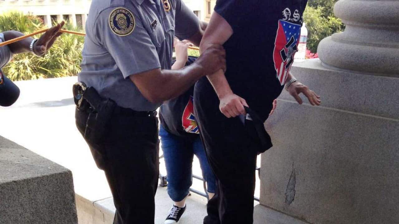 Police officer Leroy Smith, left, helps a man wearing National Socialist Movement attire up the stairs during a rally Saturday, July 18, 2015, in Columbia, S.C. (Rob Godfrey via AP)